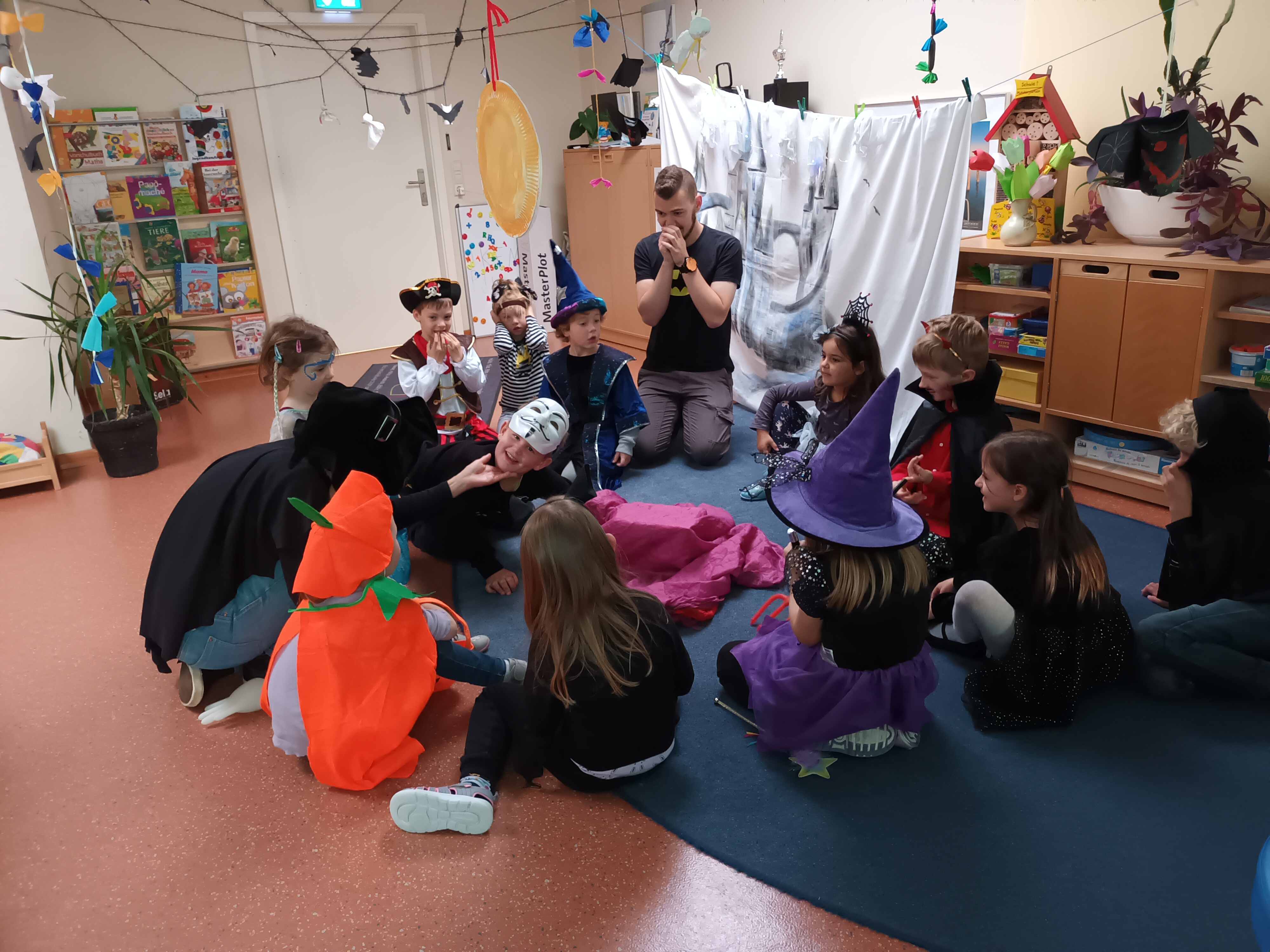 Die Kinder gruseln sich gemeinsam mit der Pädagogischen Fachkraft Tobias Oberlies beim Entdecken der Inhalte in der Halloween-Tastkiste Foto: maxpress/Meike Sump